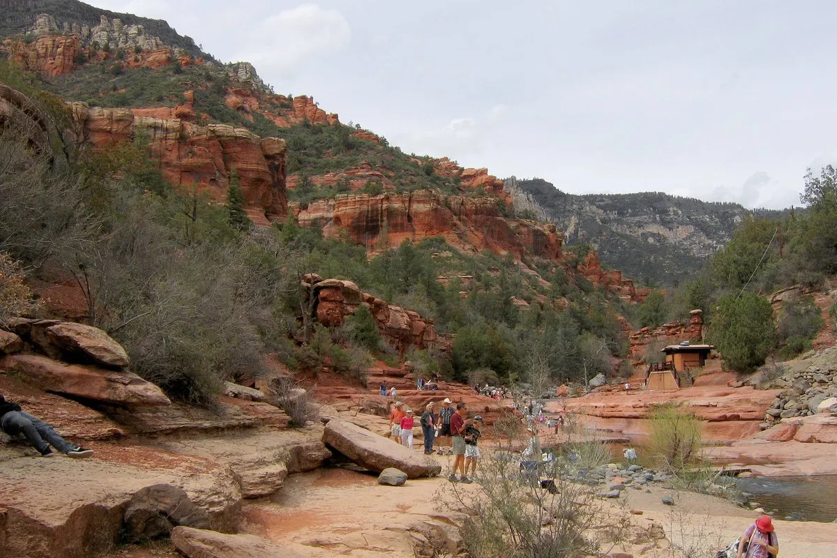 Natural red rock water slide along Oak Creek at Slide Rock State Park, Arizona, with canyon walls and lush streamside vegetation