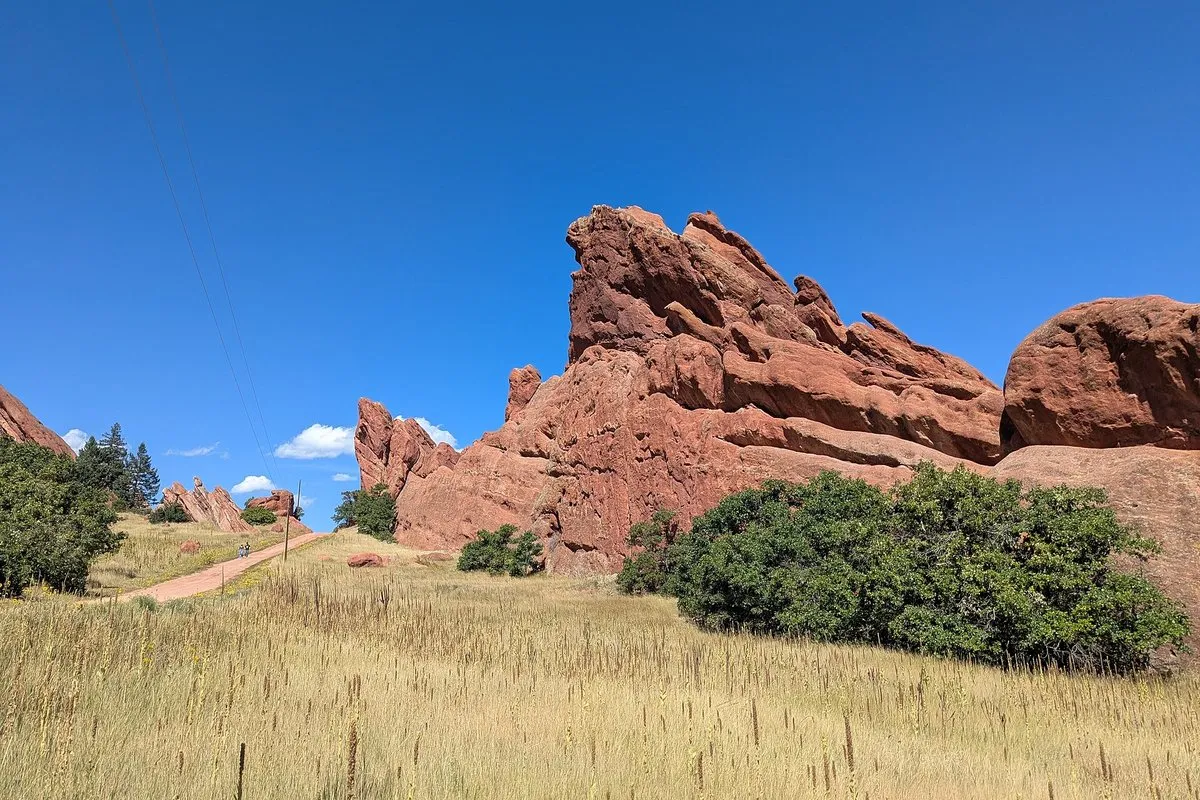 Dramatic red sandstone rock fins rising above green foothills at Roxborough State Park, Colorado