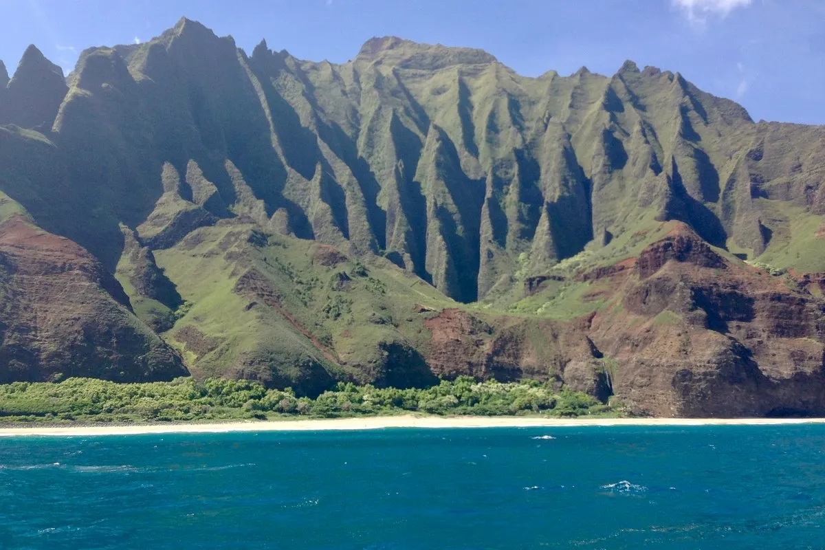 Scenic view of the rugged emerald sea cliffs of Napali Coast, Hawaii, rising above the deep blue Pacific Ocean