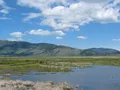 Scenic view of Henry's Lake with calm water reflecting surrounding mountains and meadows in Island Park, Idaho