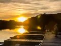 Anglers fishing from a wooden dock at sunset at Chain O' Lakes State Park, Indiana, with rowboats moored alongside