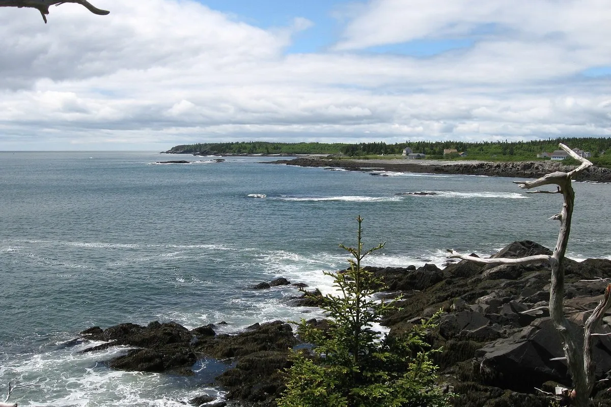 Scenic view of the red and white striped West Quoddy Head Lighthouse overlooking the rocky coastline at Quoddy Head State Park, Maine