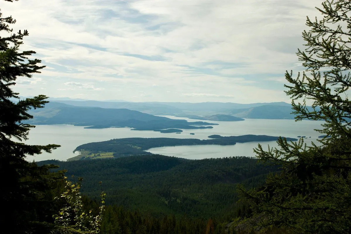 Scenic view of Flathead Lake, Montana, with calm blue water reflecting surrounding mountains and forested shoreline