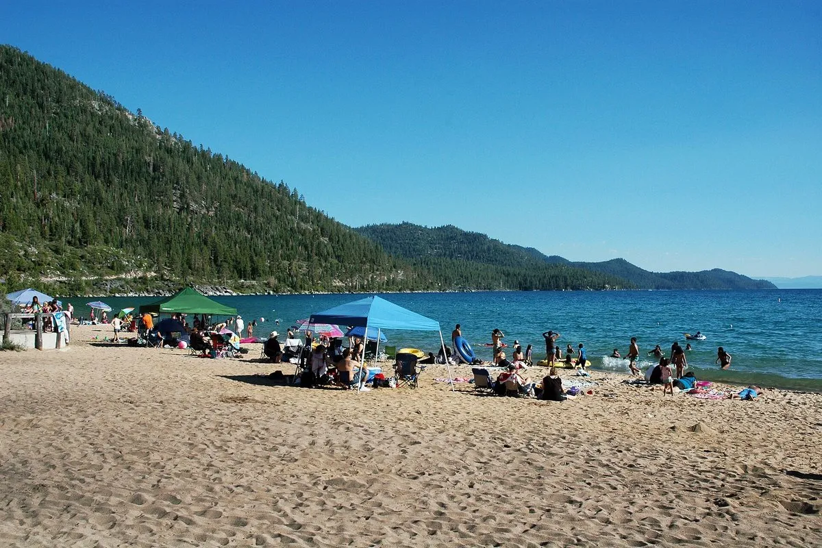 Crystal-clear turquoise waters and granite boulders along the sandy shoreline at Sand Harbor, Nevada, with forested mountains in the background