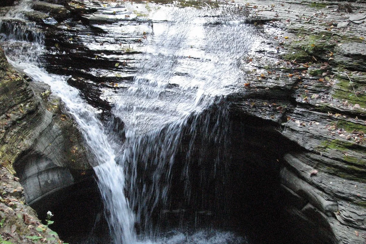 Scenic gorge trail winding past cascading waterfalls and mossy stone walls at Watkins Glen State Park, New York