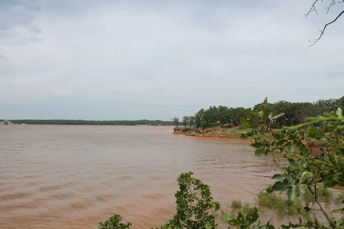Scenic view of Lake Thunderbird, Oklahoma, with calm water reflecting a blue sky and tree-lined shores