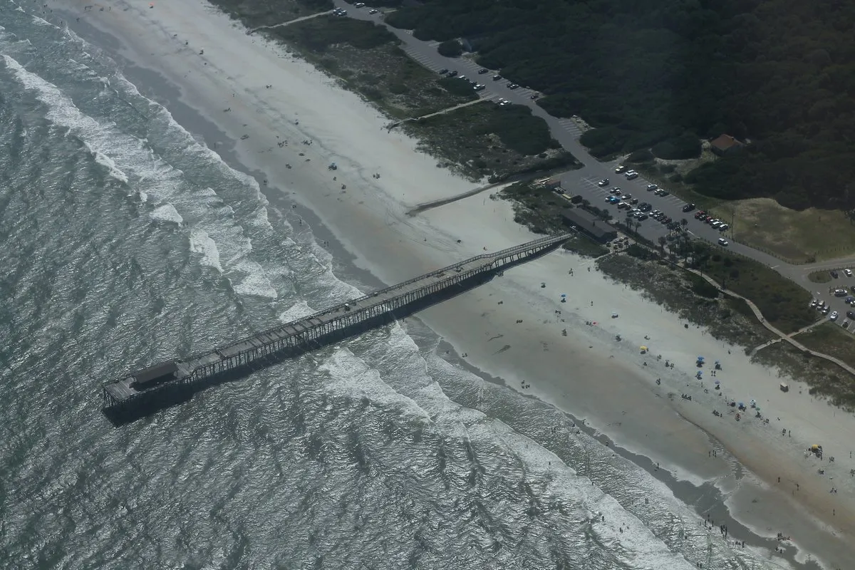Scenic view at Myrtle Beach State Park, South Carolina, showing a wide sandy beach meeting the Atlantic Ocean with blue skies overhead