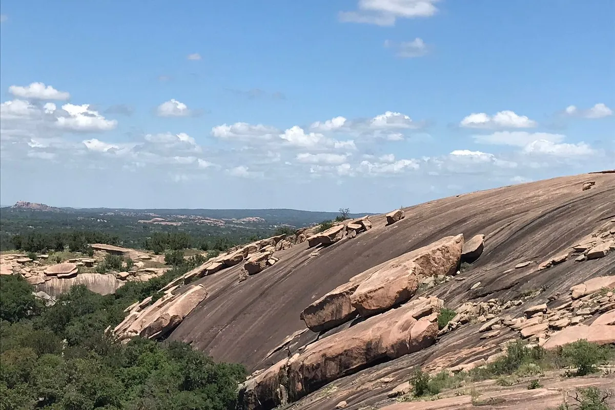Scenic view of the massive pink granite dome at Enchanted Rock rising above the Texas Hill Country landscape