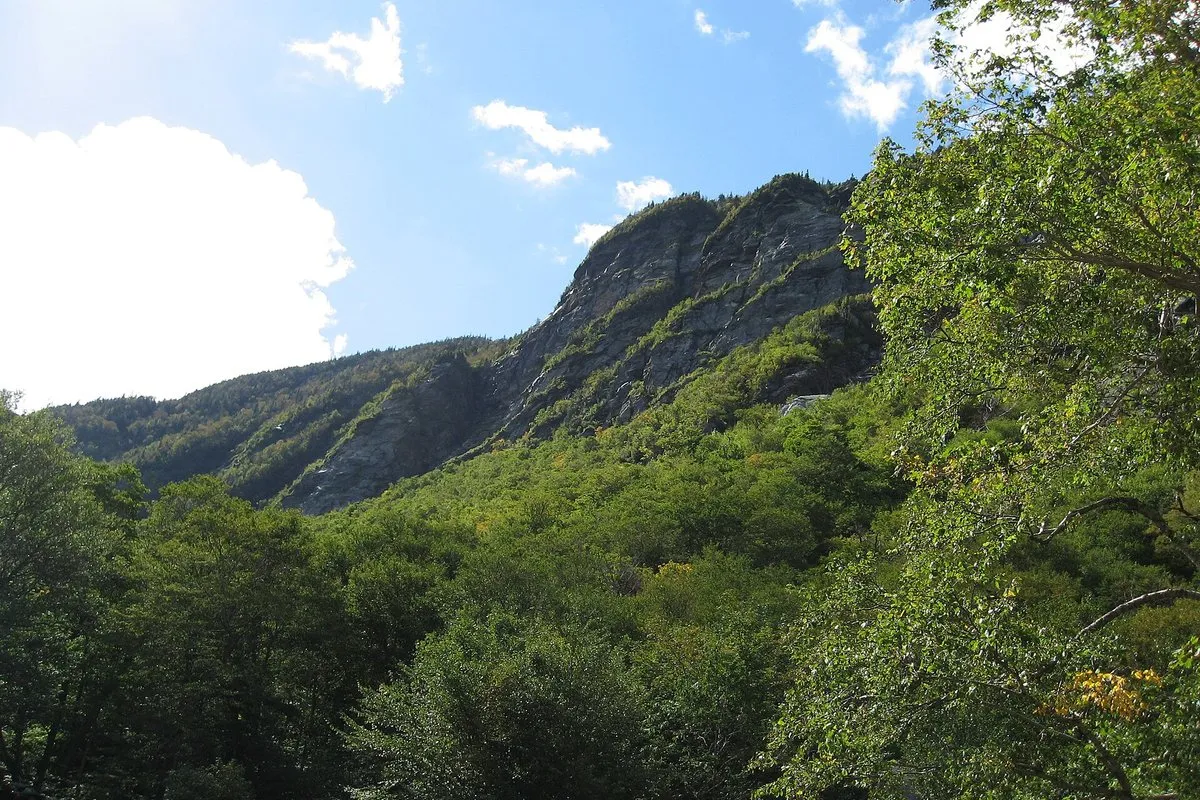 Scenic view of the rocky mountain pass at Smugglers' Notch, Vermont, with forested slopes and dramatic boulder-strewn terrain